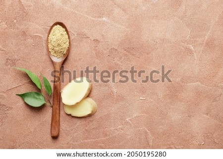 Wooden spoon full of dry ginger on textured background
