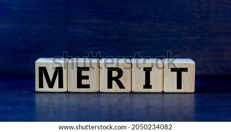 Merit symbol. The concept word 'merit' on wooden cubes on a beautiful dark grey table. Dark grey background. Business and merit concept.