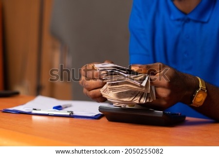 a nigerian man counting money Royalty-Free Stock Photo #2050255082