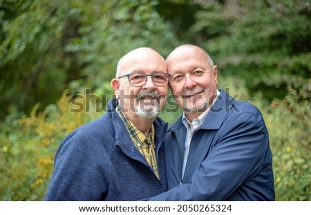 A married, elderly gay male couple embrace each other in a show of love and affection.
