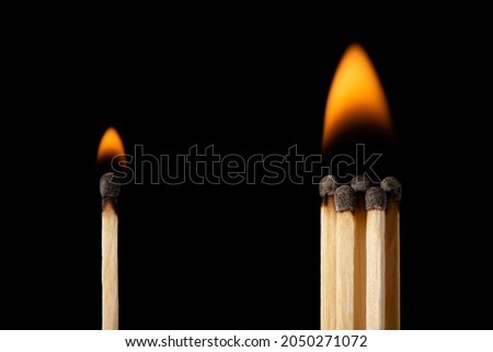 Burning safety matches on black background, one stands on the distance from the group of others. Concept of being alone and working in the group.