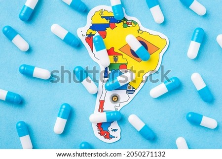 Many medical pills, capsules on top of map and flag of South America Continent. Epidemic on the continent, dangerous disease Royalty-Free Stock Photo #2050271132