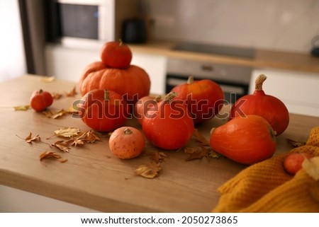 Autumn bright kitchen interior. Pumpkins and yellow fallen leaves on the kitchen wooden table. Concept of Thanksgiving day or Halloween. High quality photo