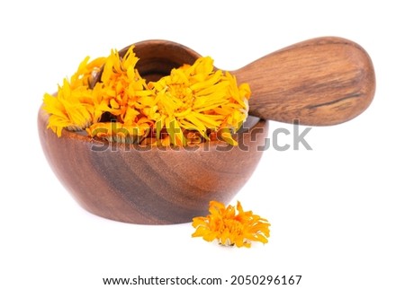 Dried calendula flowers in wooden bowl and spoon, isolated on white background. Petals of Calendula officinalis. Medicinal herbs.
