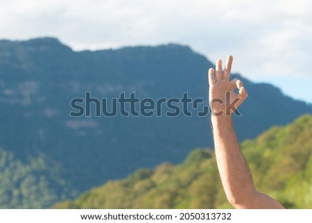 A man shows his hand an OK sign, on the background of nature in the mountains. Great trip.