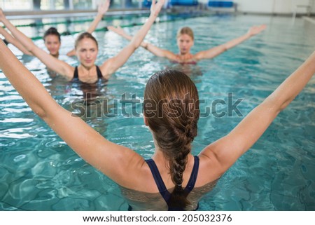 Smiling female fitness class doing aqua aerobics in swimming pool at the leisure centre Royalty-Free Stock Photo #205032376