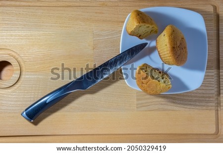 Freshly baked muffins cut with a knife on a square plate on a wooden background