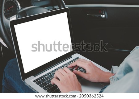 Asian woman sitting in a car typing on keyboard and using laptop computer with chroma key green screen display, social distancing during delta covid pandemic , freelance job, new normal concept