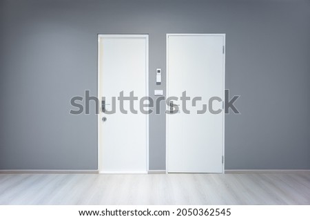 Closed wooden door inside empty room at front view. Entrance of room inside house building. Include wooden floor or laminate, gray wall. New clean surface of wooden texture look modern at night.