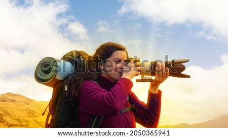 Close up of a beautiful Hispanic female scout with a backpack taking a photo with a telephoto lens on a morning