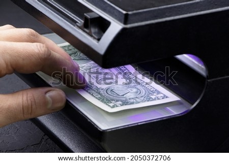 Examining dollar banknote with a money detector.Detector banknotes.Counterfeit money.Money in the ultraviolet light.watermarks on banknotes.on banknotes.