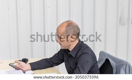 An attractive male office worker is using a smartphone to check his business and market information online. Business man use digital device to enhance his marketing. A man is chatting with his friends