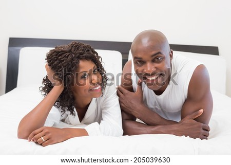 Happy couple lying on bed together at home in the bedroom