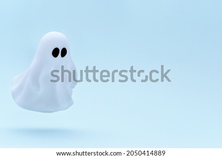 Flying white ghost toy on a gradient blue background. Minimal Happy Halloween scary concept. Creative photo of levitation.