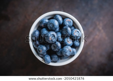 Blueberries in ceramic bowl on rustic wooden background. Selective focus. Shallow depth of field.
