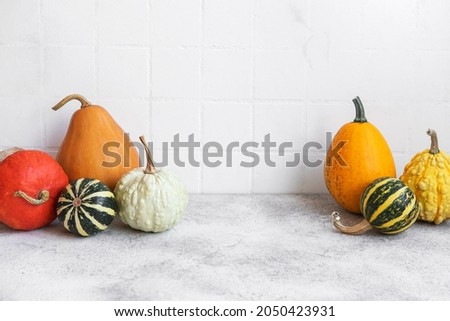 Pumpkin decor on the table over white tile background. Fall season greeting card.