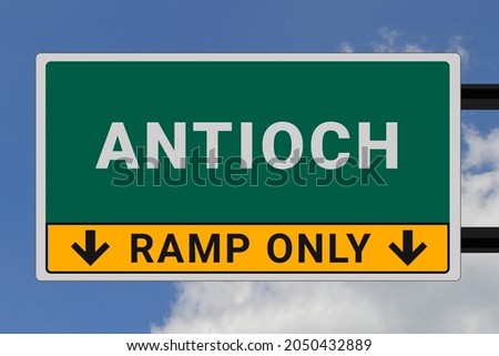 Antioch logo. Antioch lettering on a road sign. Signpost at entrance to Antioch, USA. Green pointer in American style. Road sign in the United States of America. Sky in background