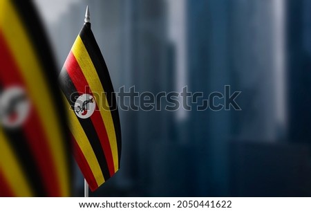 Small flags of Uganda on a blurry background of the city Royalty-Free Stock Photo #2050441622