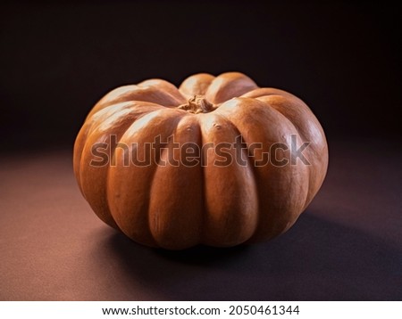 Pumpkin close-up on a black background in isolation. Soft mystical lighting with highlights, flare, flicker in the frame. Autumn theme. The holiday of Halloween. Royalty-Free Stock Photo #2050461344