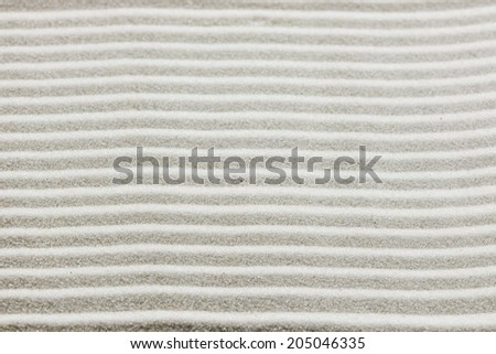 Background pattern of raked white sand in parallel lines in a zen garden in a concept of wellness, spirituality and meditation.
