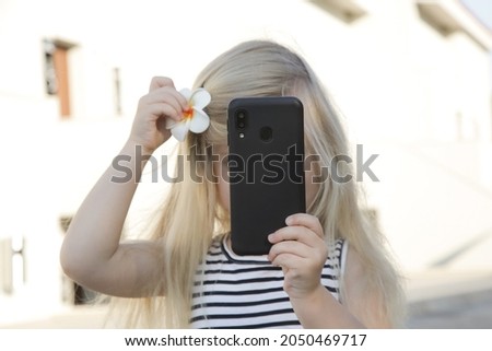 Portrait of toddler girl holding cellphone and taking photo	
