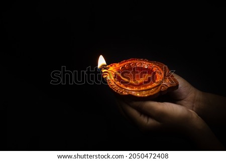 Happy Diwali. Close up of a clay diya a girl holding to celebrate and welcome the India's festival of light diwali. Royalty-Free Stock Photo #2050472408