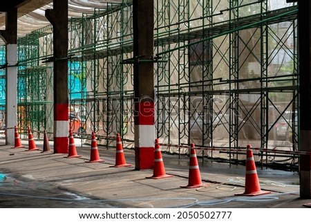 An orange rubber cone was placed as a protective line between the steel frame and the walkway in the construction area.