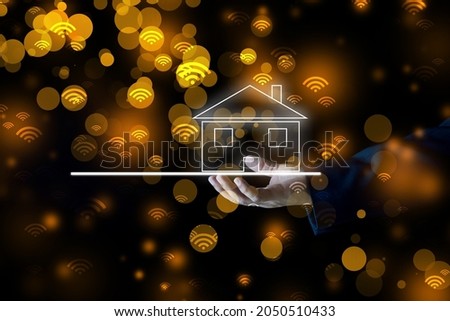 businessman holding house icon glowing white with wifi on black background golden bokeh real estate investment and finance concept.