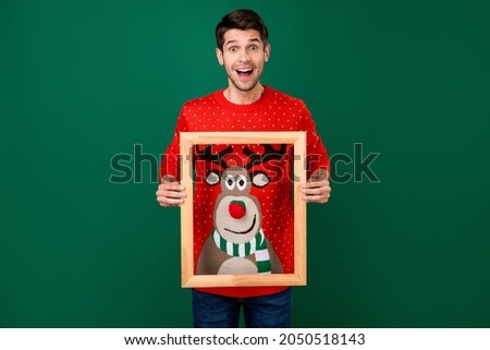 Photo portrait man in red knitted pullover on christmas smiling keeping wooden border isolated green color background