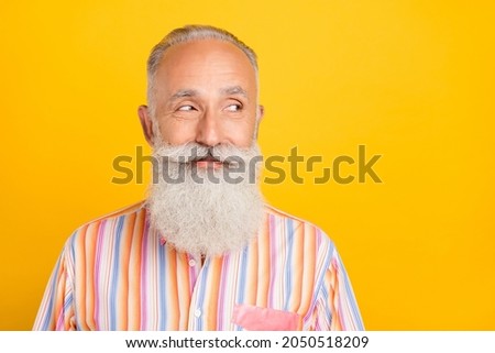 Photo of dreamy thoughtful age gentleman wear striped shirt looking empty space smiling isolated yellow color background