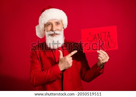 Photo of adviser santa claus finger directing sale poster wear x-mas hat suit on red color background