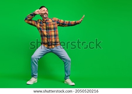 Full length body size view of attractive cheerful man dancing showing v-sign isolated over bright green color background