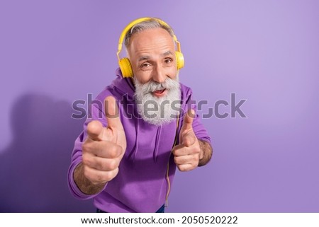 Portrait of trendy elderly retired pensioner cheerful grey-haired man listening music select pick you isolated over purple violet color background