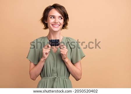 Photo of curious lady showing debit card look empty space wear green dress isolated beige color background