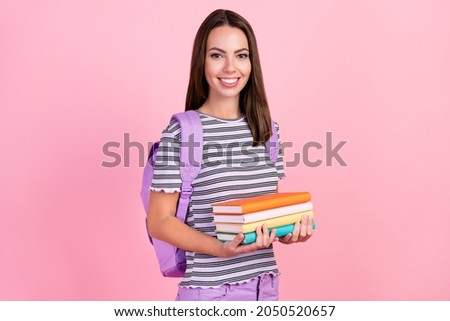 Photo of pretty shiny young lady wear striped outfit backpack smiling holding copybooks isolated pink color background