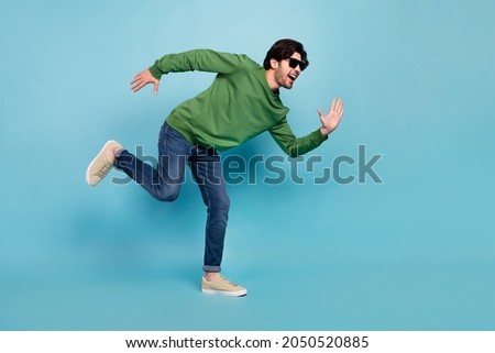 Full body photo of young good mood handsome guy in sunglass run fast speed isolated on blue color background