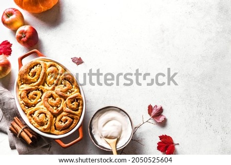 Autumn pumpkin apples cinnamon rolls and organic pumpkins and apples on white background, top view, copy space. Seasonal autumn homemade pastry - cinnabons for breakfast.