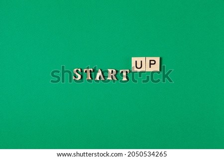 Word Startup made of wooden letters on a green background