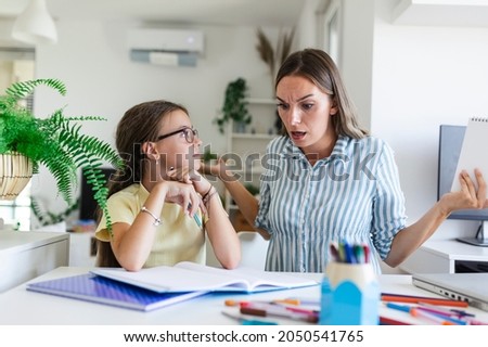 Stressed mother and daughter frustrated over failure homework, school problems concept. Sad little girl looking at mother, does not want to do boring homework