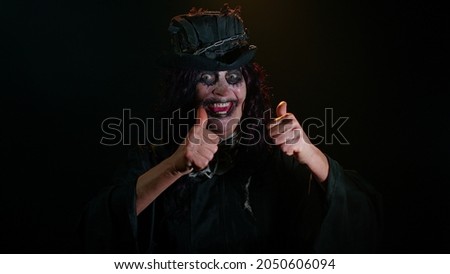 Sinister mature woman grandmother with Halloween stylish witch makeup. Old scary granny celebrate success win scream rejoices doing winner hands gesture say Yes. Voodoo. Sinister senior lady vampire