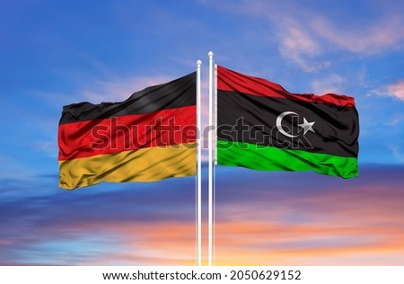 Libya and Germany flag waving in the wind against white cloudy blue sky together. Diplomacy concept, international relations