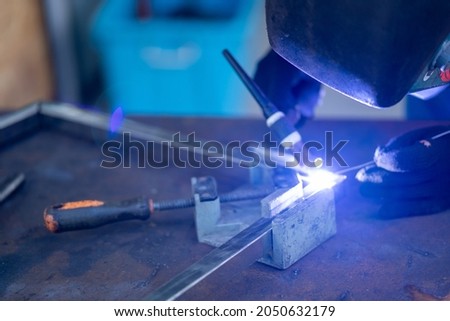 Male worker welding stainless steel sparks during welding
