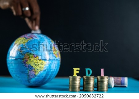 Focus on FDI letters on coins, Concept of FDI or foreign direct investment, Showing by placing coins inside the globe from behind Royalty-Free Stock Photo #2050632722