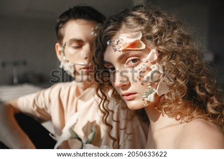Emotional portrait of a boy and girl with flowers on their face