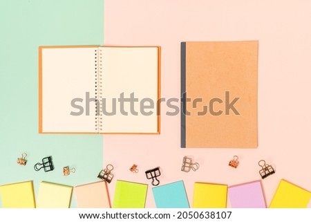 Creative flat lay photo of workspace desk. Top view office desk with adhesive note and open mockup black notebook on pastel green pink color background. Top view mock up with copy space photography.