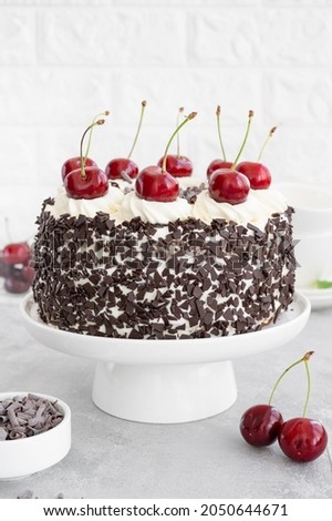 Black forest cake, Schwarzwald pie. Cake with dark chocolate, whipped cream and cherry on a gray concrete background. Copy space