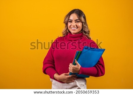 Smiling plus size woman student with school books in hands on yellow background.