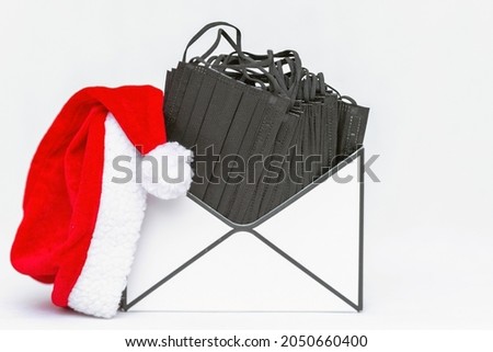 Santa hat,Present, gift Letter envelope box open with protective masks inside. White gray background. Holidays, and partys during coronavirus social distance New Year 2022 concept.Indoors shot.
