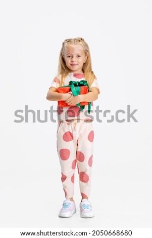 Birthday present. Cute caucasian child with gift box isolated over white background. Looks happy, cheerful. Childhood, family, happiness, education, emotions, facial expression concept, ad