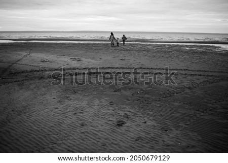 Mom with two kids running on the beach on a cold autumn evening